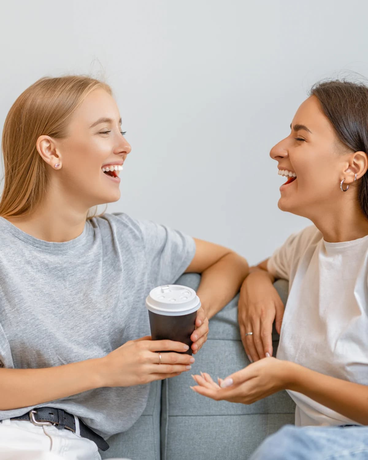 Two women laughing together over coffee.